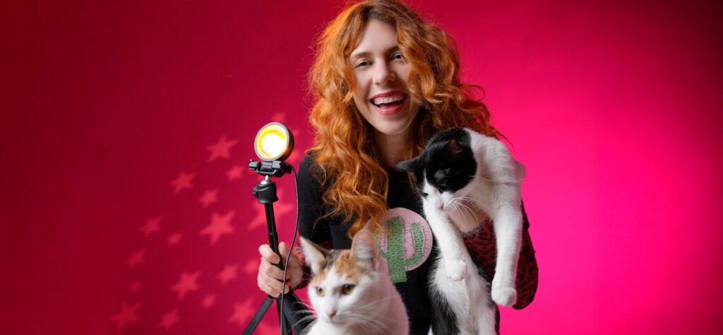 Lorena Riga en su estudio Fotográfico de Madrid haciendo contenido de su Marca Personal para su canal de YouTube, en sus manos sostiene a sus dos gatos adoptados Milton y Anastasia y una lampara de Luz del Atardecer.