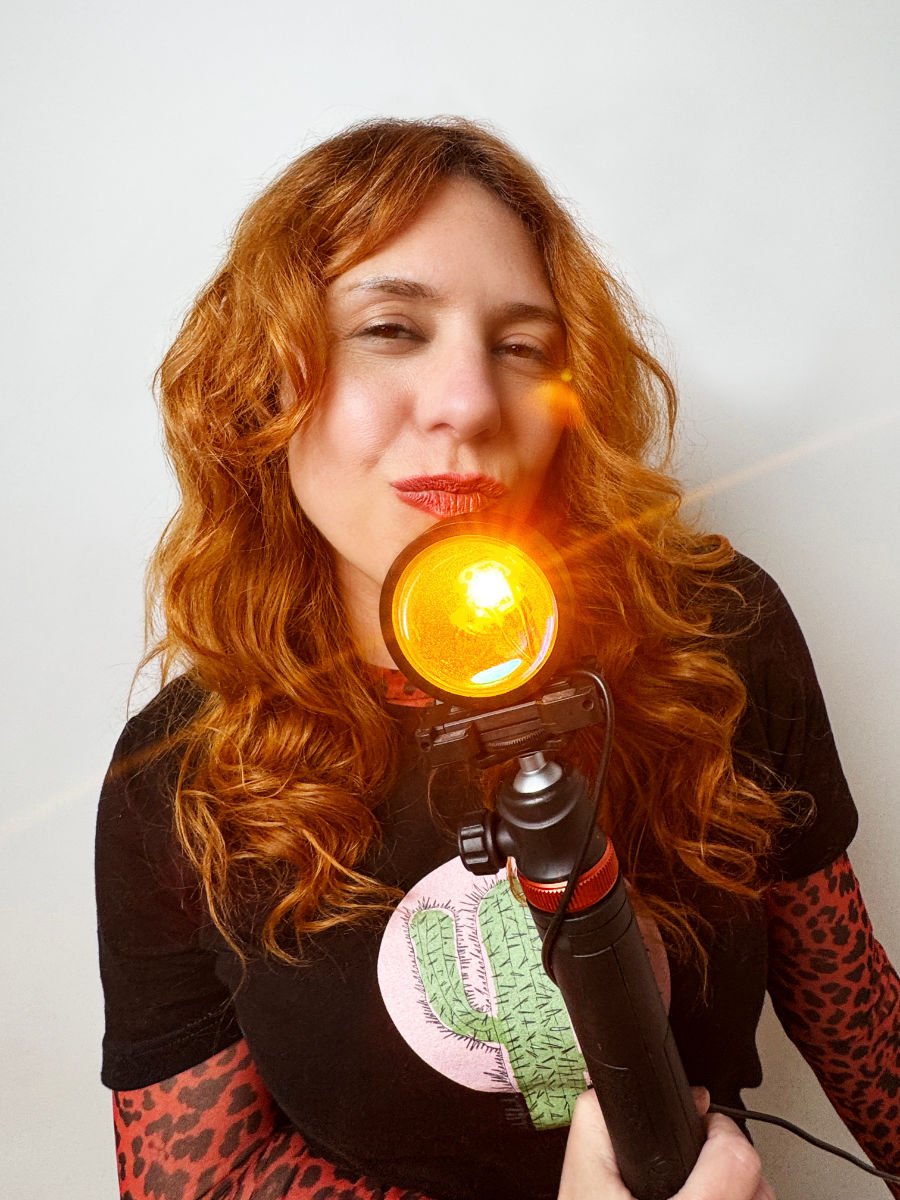 Lorena Riga en su estudio fotográfico de Madrid sostiene en sus manos un lampara de Luz del Atardecer vistiendo una camiseta de missfolk