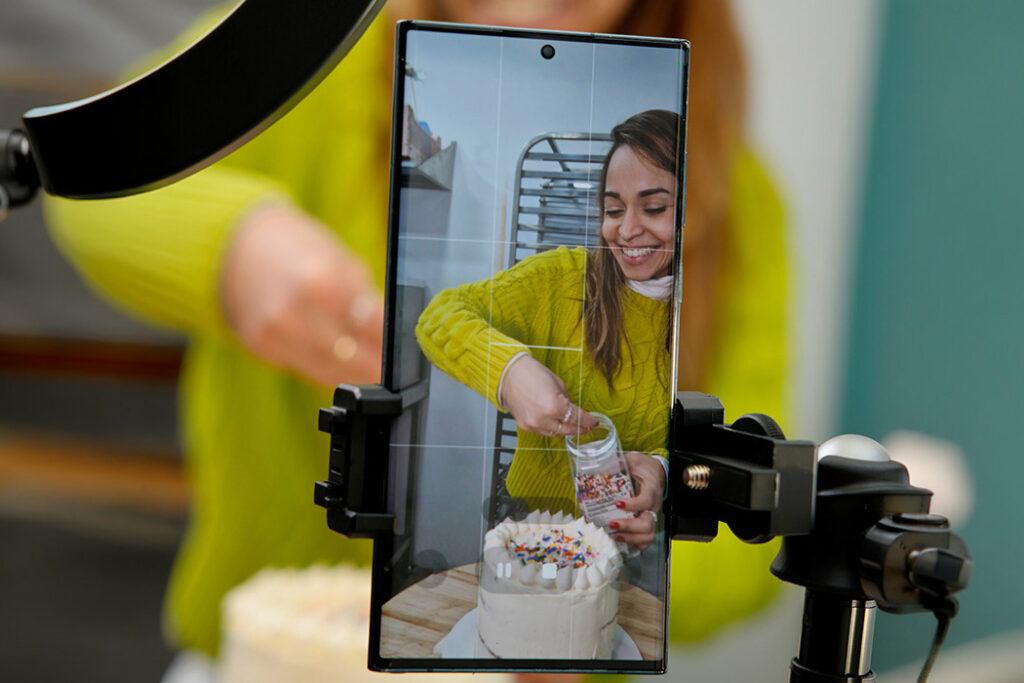 mujer grabandose con el movil creando contenido para reels de ella haciendo una tarta